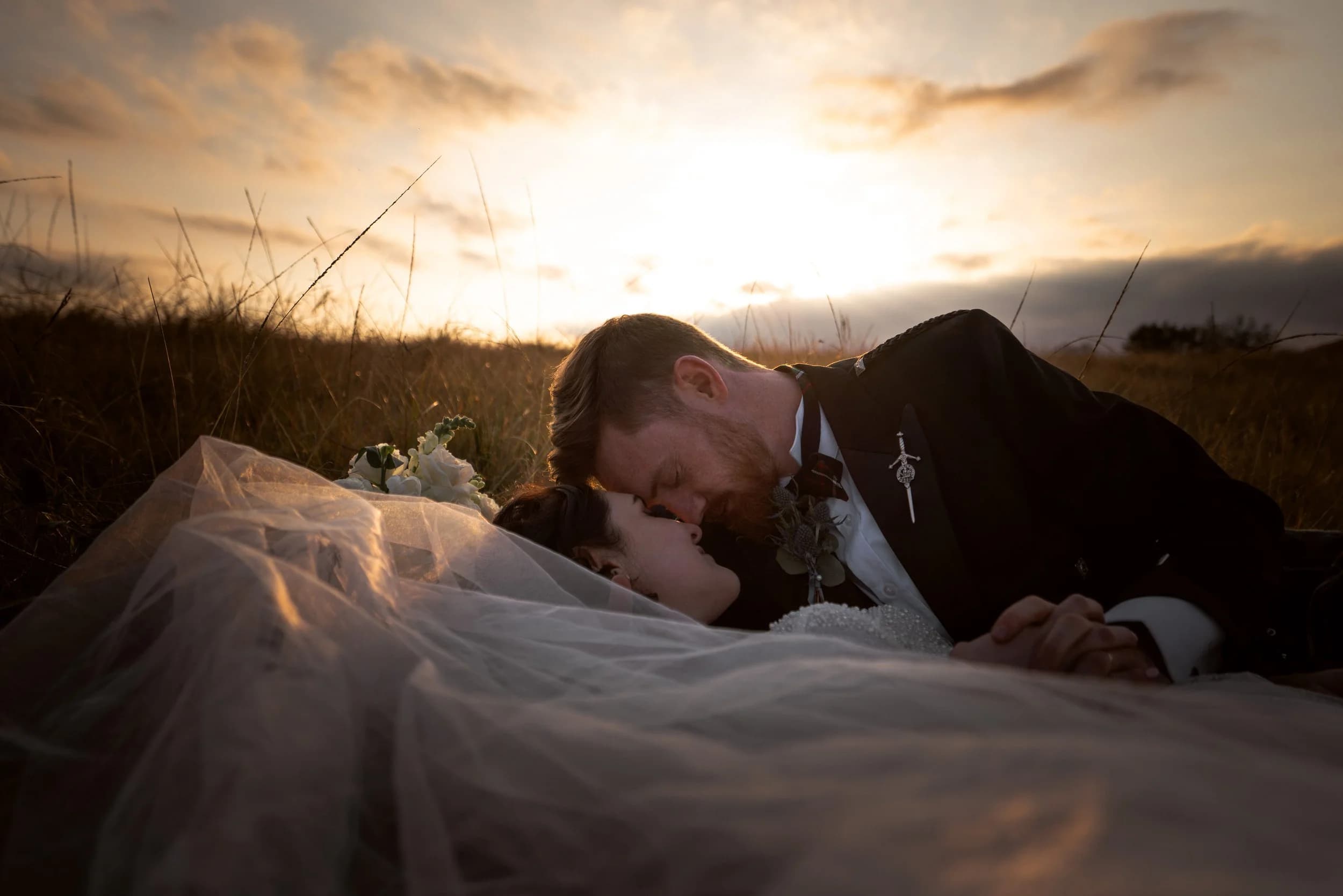 Bride and groom in the grass at sunset at Netherwood